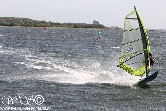 Hans windsurfing on open water, the sail tilted in the wind